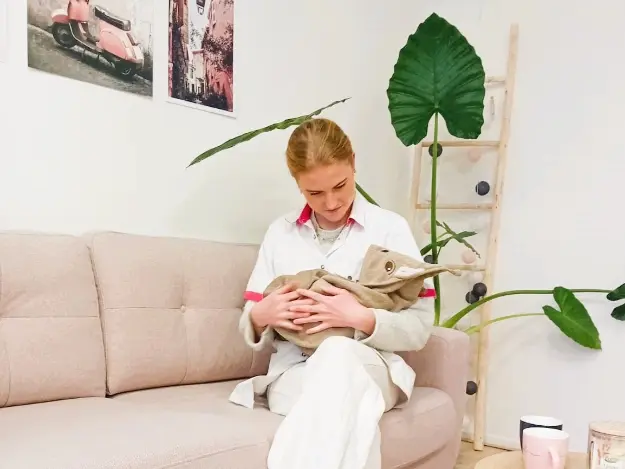 Kraamverzorgende zittend op een bank met een baby